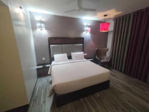 une chambre avec un lit blanc et une chaise dans l'établissement POP 84200K M K Elegance Inn, à Coimbatore (Peelamedu) 3 autres photos