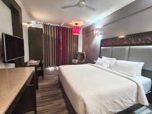 une chambre d'hôtel avec un grand lit et une télévision dans l'établissement POP 84200K M K Elegance Inn, à Coimbatore (Peelamedu)
