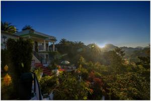 ein Haus auf einem Hügel, hinter dem die Sonne aufgeht in der Unterkunft Green Valley Resort in Mount Ābu