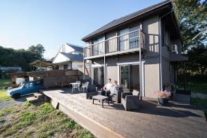two people sitting on a deck in front of a house at Vacation Rental NENBA in Hokuto