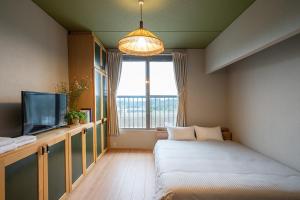 a room with a couch and a tv and a window at Vacation Rental NENBA in Hokuto