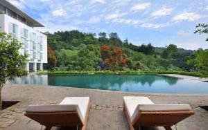 einem Pool mit zwei Sofas vor einem Gebäude in der Unterkunft Padma Hotel Bandung in Bandung