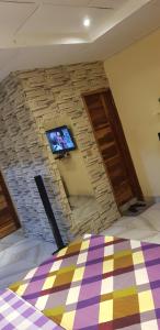una camera da letto con TV su un muro di pietra di Résidence Yamoussoukro a Yamoussoukro