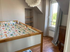 a bedroom with a bed with a comforter and a window at Appartement centre in Quiberon