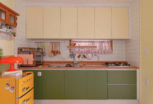 een keuken met groene kasten en een spoelbak bij The Cozy Oven in Busan +19 foto's