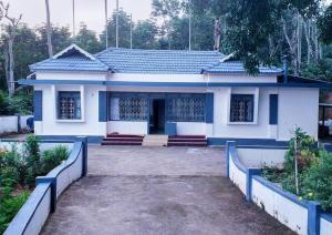 a small white house with a blue roof at The Coffee Cube in Kaniyāmbetta +4 photos