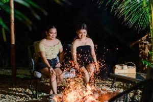 two women sitting around a fire on the beach at Tongo Hill Cottages in Moalboal