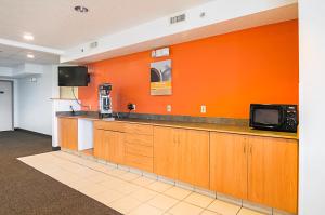 a kitchen with an orange wall and a microwave at Motel 6-Sycamore, IL in Sycamore