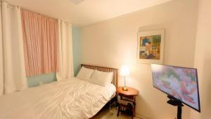 een kleine slaapkamer met een bed en een televisie bij The Cozy Oven in Busan