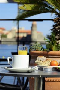 a cup of coffee and a plate of bread on a table at Hôtel Triton in Collioure