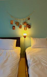 een slaapkamer met twee bedden en een lamp, met schilderijen aan de muur bij The Cozy Oven in Busan