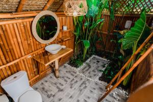 ein Badezimmer mit Waschbecken und Spiegel an einer Holzwand in der Unterkunft Tongo Hill Cottages in Moalboal