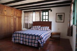 a bedroom with a bed with a checkered blanket at Finca Villa Sofía in Villa de Leyva +18 photos