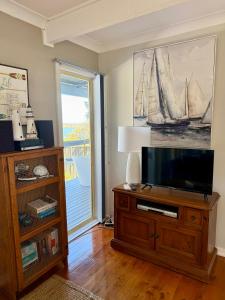 a living room with a flat screen tv on a wooden entertainment center at Lakeview Cottage in Forster