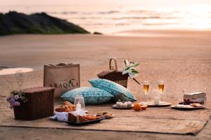 a picnic on the beach with food and champagne glasses at Araqila in Vengurla