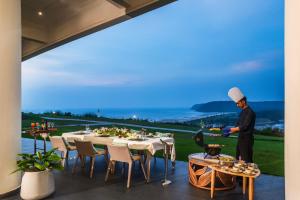 a man standing on a patio with a table at Araqila in Vengurla
