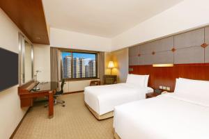 a hotel room with two beds and a desk at Shangri-La Harbin in Harbin