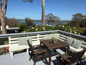 a wooden table and chairs on a wooden deck at Lakeview Cottage in Forster