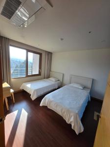 a bedroom with two beds and a window at Hallasan Resort in Sanch'ŏndan +28 photos