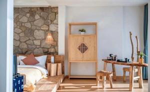 a bedroom with a bed and a wooden table at Nanshe Nan Inn Dali in Dali Airport