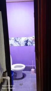 a bathroom with a white toilet in a purple wall at Ingeritch Cabin Transient and Homestay in Baguio