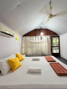 een slaapkamer met een groot wit bed met gele kussens bij Lacto Cressida in Palolem