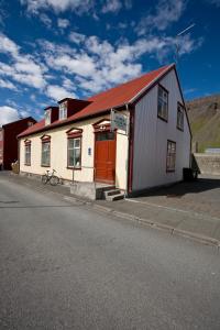 een wit gebouw met een rood dak op een straat bij Guesthouse Ísafjördur - Gamla in Ísafjörður