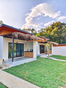 a house with a thatched roof and a yard at Ingtara at Lanta in Ko Lanta