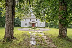 a white house with a red door between two trees at HAL484-Unnaryd-Yas-108 in Unnaryd