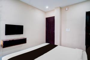 a bedroom with a bed and a flat screen tv at Hotel O The Pride Inn Basistha Road in Khānāpāra +22 photos