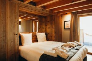 - une chambre avec un grand lit et des murs en bois dans l'établissement Les Framboisiers by Lodji, à Saint-Marcel