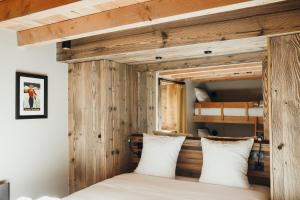 une chambre avec des murs en bois et un lit avec des oreillers blancs dans l'établissement Les Framboisiers by Lodji, à Saint-Marcel