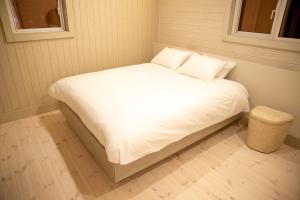 un lit avec des draps blancs et des oreillers dans une chambre dans l'établissement Lucent NISEKO, à Niseko
