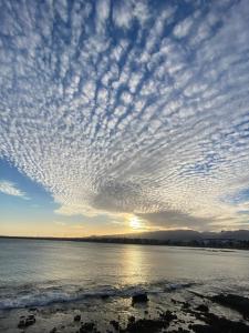 a cloudy sky over the water with the sunset at MarMontaña in Arinaga