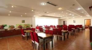 ein Restaurant mit roten Stühlen und Tischen in einem Raum in der Unterkunft GreenTree Inn Tianjin Wuqing Distric Bohai Market in Dadunqiu