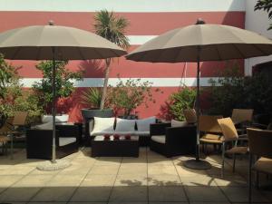 a patio with couches and tables and umbrellas at Hotel Cote Patio in Nîmes