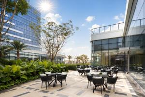 eine Terrasse mit Tischen und Stühlen vor einem Gebäude in der Unterkunft Courtyard by Marriott Xiamen Xiang’an in Xiamen