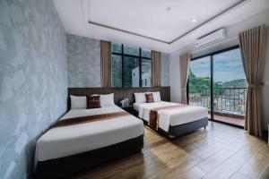 een hotelkamer met twee bedden en een balkon bij Véra Stay - Cat Ba in Cat Ba