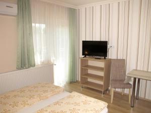 a room with a television and a desk with a chair at Csilla apartman in Hajdúszoboszló