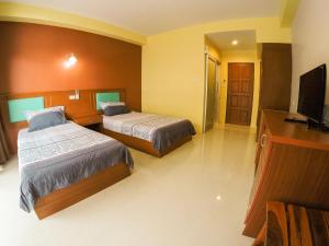 a hotel room with two beds and a flat screen tv at Madam House in Karon Beach