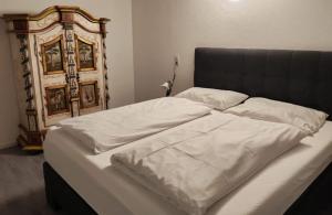 a bed with white sheets and a wooden headboard at Family & Friends in Hopfgarten im Brixental