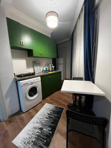 a kitchen with green cabinets and a table and a washing machine at Nehir Apart Hotel in Fethiye