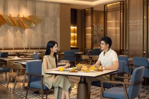 zwei Personen sitzen an einem Tisch in einem Restaurant in der Unterkunft Courtyard by Marriott Xiamen Xiang’an in Xiamen