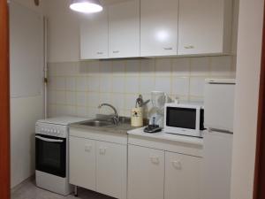 ポリニャーノ・ア・マーレにあるDimora Tarantiniの白いキャビネット、シンク、電子レンジ付きのキッチンが備わります。