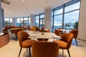 a restaurant with tables and chairs and large windows at Ramla Bay Resort in Mellieħa