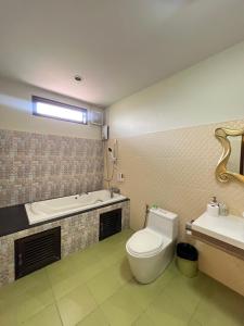 a bathroom with a toilet and a tub and a sink at Excellence Pool Villa in Na Jomtien