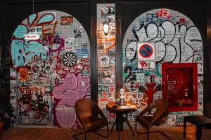 een muur vol graffiti met een tafel en stoelen bij The Quartier Hotel Phromphong - Thonglor in Bangkok