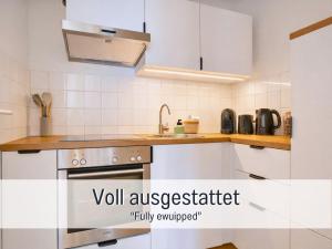 une cuisine blanche avec un évier et une cuisinière dans l'établissement Altstadt Suite mit Parkplatz, à Cobourg