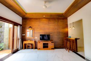 a living room with a tv and a wooden wall at Dupa Ubud in Ubud