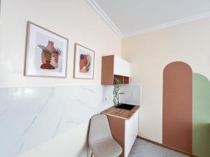 une pièce blanche avec une chaise et deux tableaux au mur dans l'établissement Bekarys Hotel, à Astana 18 autres photos